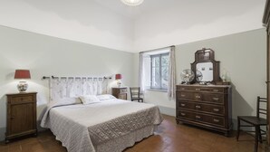 A bedroom with a bed, dresser, nightstands, and a window with curtains. - Orcia Panoramic View With Pool (Sarteano)