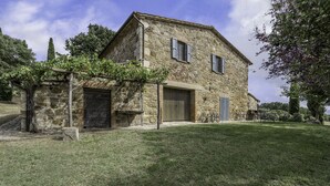A stone house with a large garage and a covered outdoor seating area. - Orcia Panoramic View With Pool (Sarteano)