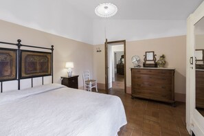 Ein Schlafzimmer mit Bett, Schminktisch, Stuhl und Spiegel.