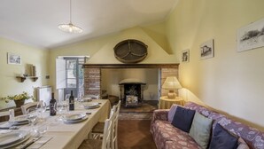 A dining area with a long table set for a meal, a fireplace, and a sofa in the foreground. - Orcia Panoramic View With Pool (Sarteano)