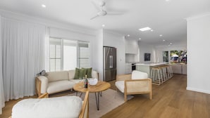A modern living room with a sofa, a round coffee table, and a dining area with bar stools.