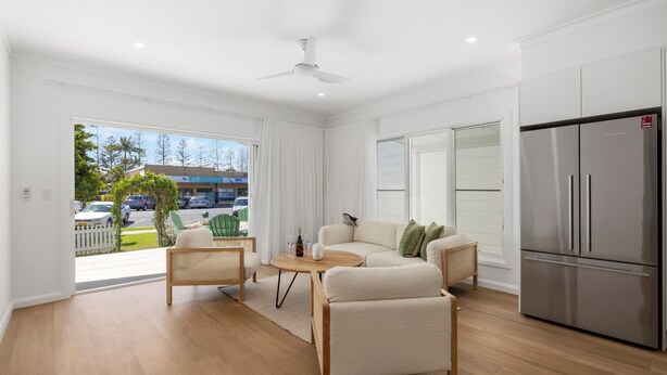 A modern living room with a sofa, chairs, a table, and a refrigerator.