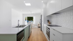 A modern kitchen with white cabinetry, a central island, and a view to the outside.