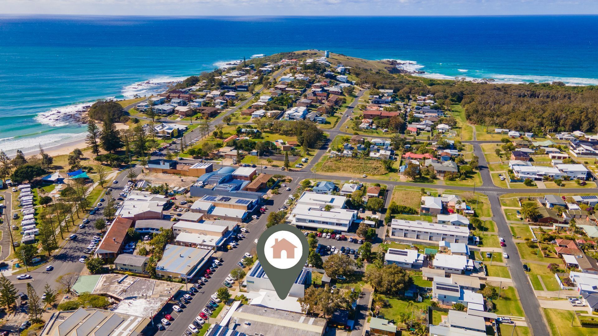 An aerial view of a coastal residential area with houses, roads, and a beach.
