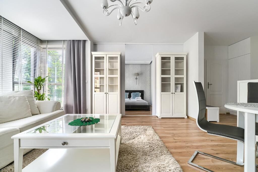 Ett modernt vardagsrum med ett soffbord i glas, en soffa, en matplats med en stol och inbyggda hyllor.