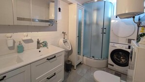 A bathroom with a toilet, sink, urinal, and washing machine. - Marijano Dvosobni Apartman s Vrtom (Zadar)