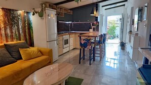 A modern kitchen with a dining area, a sofa, and a coffee table. - Marijano Dvosobni Apartman s Vrtom (Zadar)