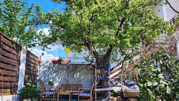 A backyard with a wooden deck, a hammock, and a small table with chairs. - Marijano Dvosobni Apartman s Vrtom (Zadar)