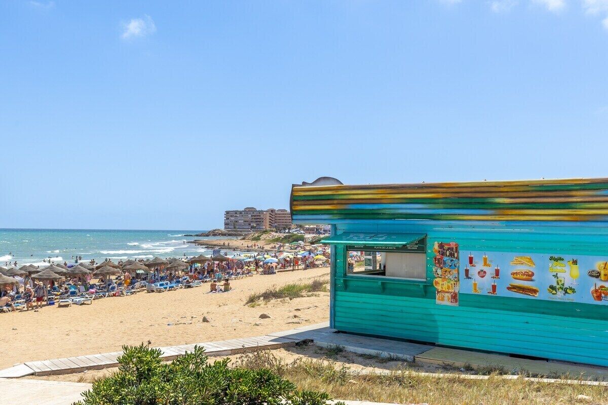 A beachside building with a green exterior and a signboard displaying food items.