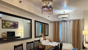 A hotel room with a bed, a dining table with chairs, a TV, and two large mirrors. - 2BR Poolview  for 6-10 pax at Sea Residences Mall of Asia 402403 (Pasay)