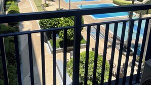 A residential building with multiple balconies, a swimming pool, and palm trees. - 2BR Poolview  for 6-10 pax at Sea Residences Mall of Asia 402403 (Pasay)