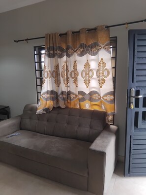 Una sala de estar con un sofá, una cortina de estampado geométrico y una puerta de diseño calado.