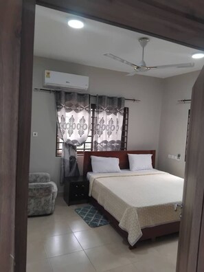 A bedroom with a bed, a nightstand, a chair, a window with curtains, an air conditioner, and a ceiling fan. - Family friendly,calm environment (Tema)