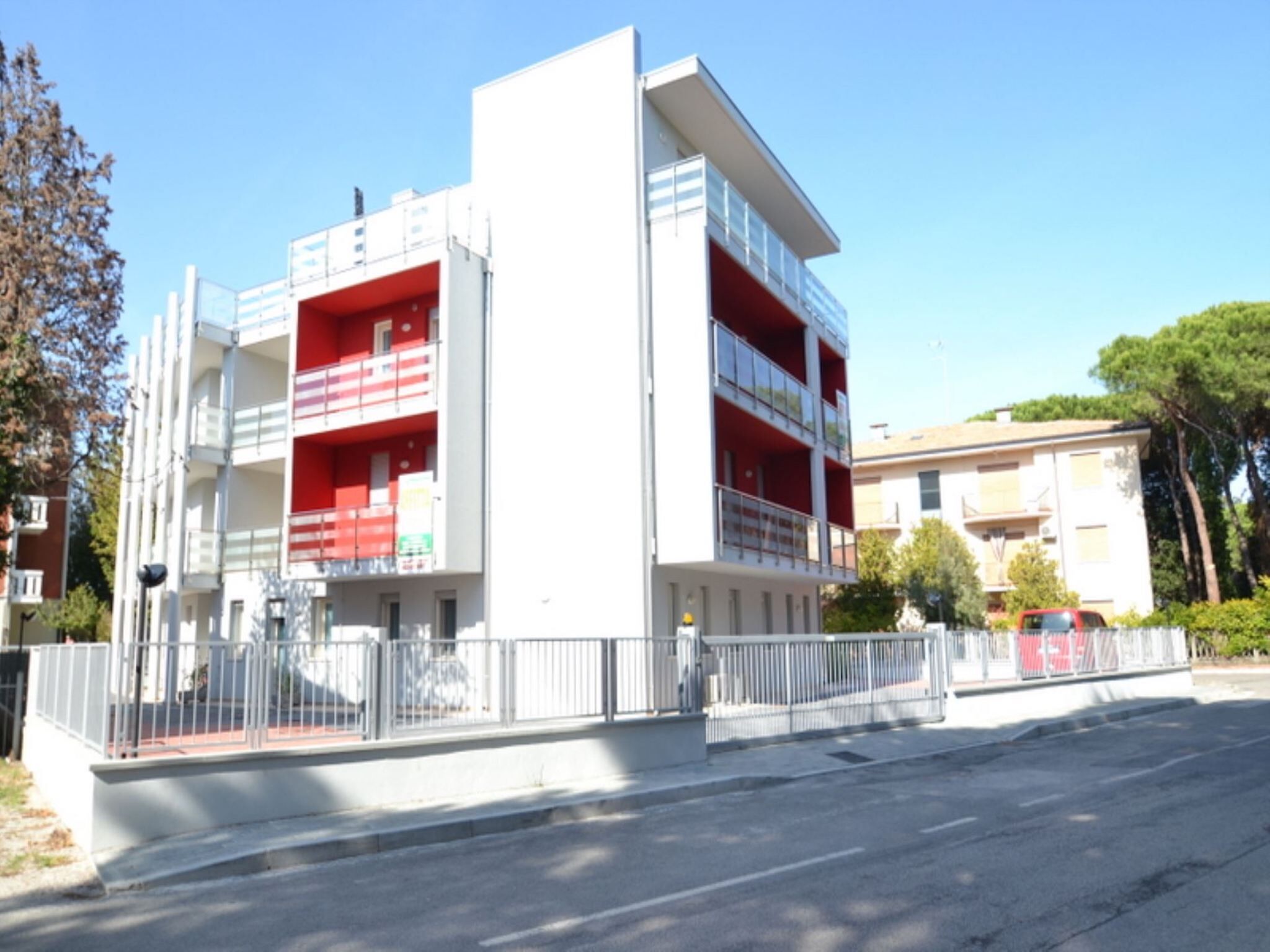 Um edifício moderno de vários andares com varandas e portão fechado.