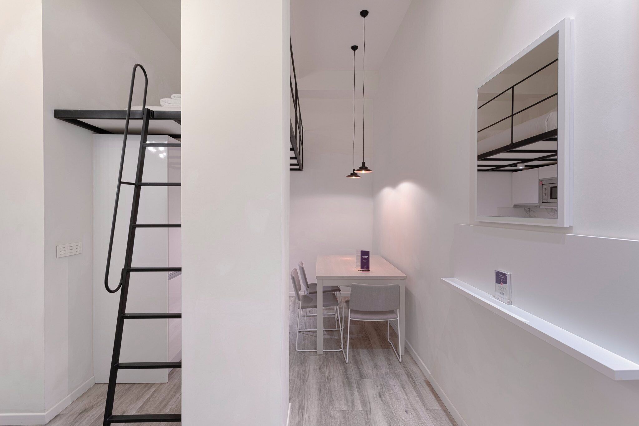 A compact room with a bunk bed, a dining table with chairs, and pendant lighting.