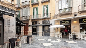 An outdoor café area with stone flooring, bar stools, and tables. - Fresh Velazquez Apartments (Málaga)