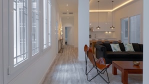 A spacious living area with a sofa, a dining table, and a kitchen in the background. - Fresh Velazquez Apartments (Málaga)