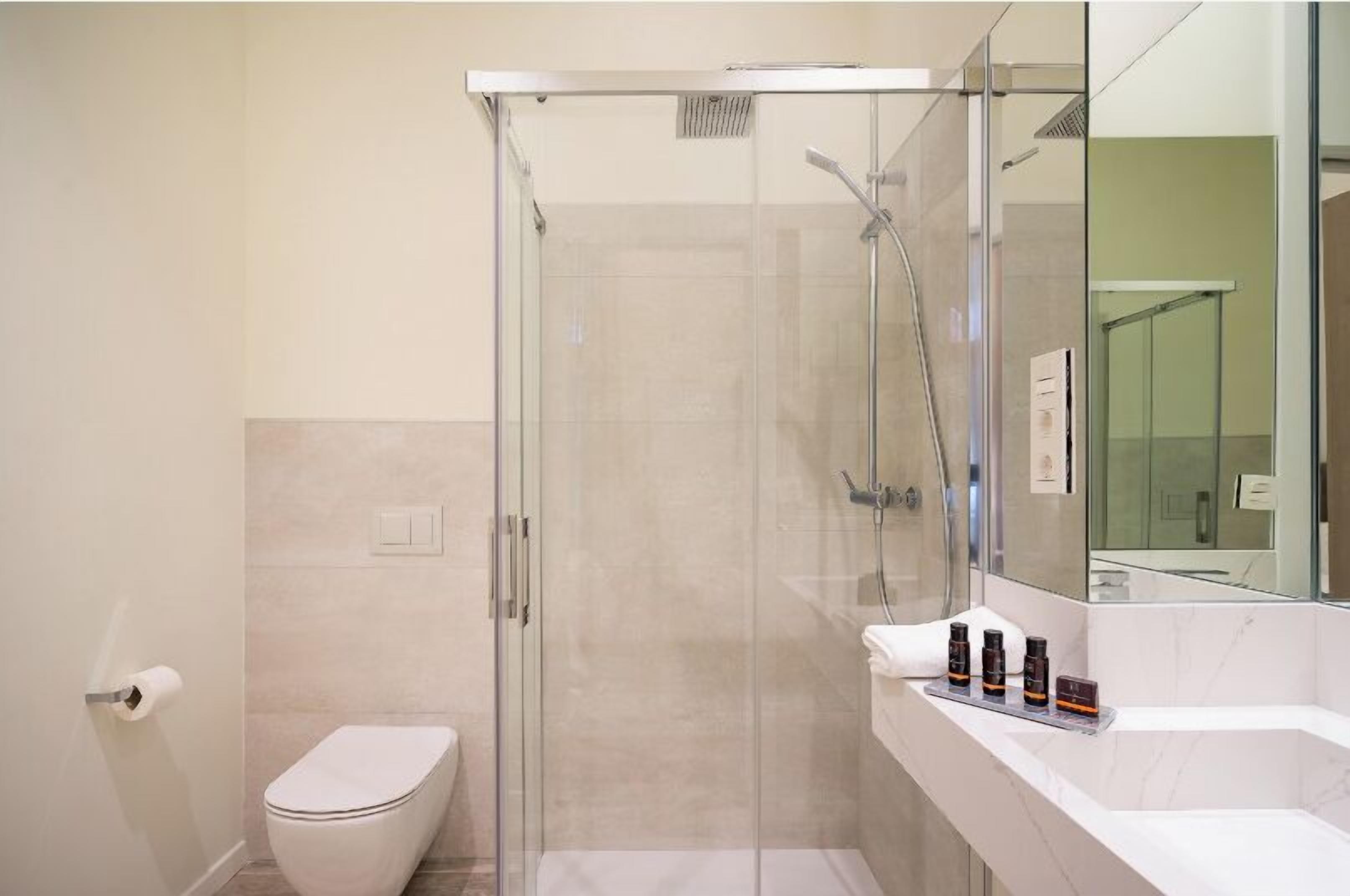 A modern bathroom with a glass-enclosed shower, a toilet, and a vanity with toiletries.
