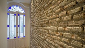 A room with a stone wall and a white door with blue-tinted glass panels. - Fresh Velazquez Apartments (Málaga)