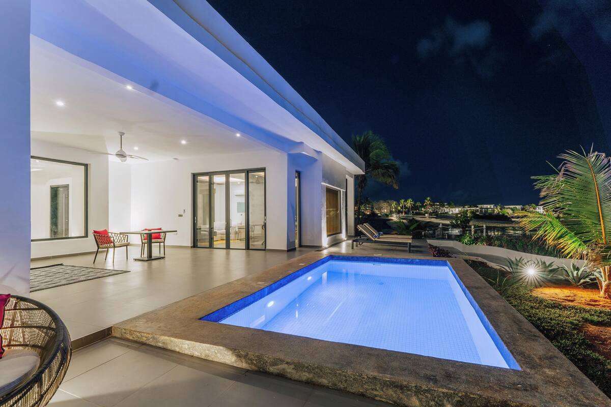 A modern house with a swimming pool, a dining area, and a patio with outdoor furniture.