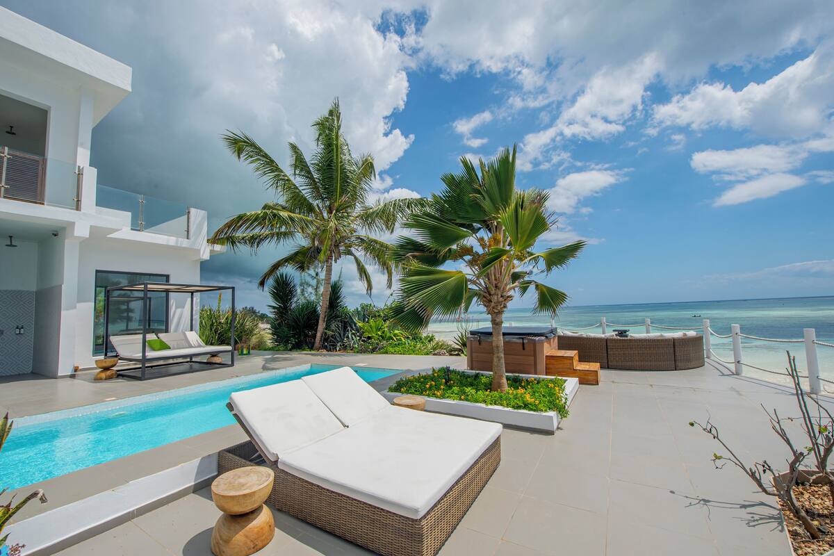 A modern poolside area with a lounge chair, a small pool, and a view of the ocean.
