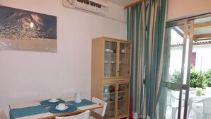 Un coin repas avec une table dressée pour deux personnes, un meuble avec des portes en verre et une vue sur l’extérieur grâce à une porte coulissante.