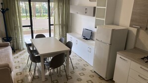 A compact kitchen with a dining table and chairs, a refrigerator, and a small countertop with a sink.