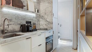 A modern kitchen with marble countertops, a built-in oven, and a coffee machine. - The Lander - Serviced 1BR/1BA - Louvre-Rivoli III (Paris)
