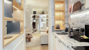 A modern kitchen with marble countertops, built-in shelves, and a black coffee machine. - The Lander - Serviced 1BR/1BA - Louvre-Rivoli III (Paris)