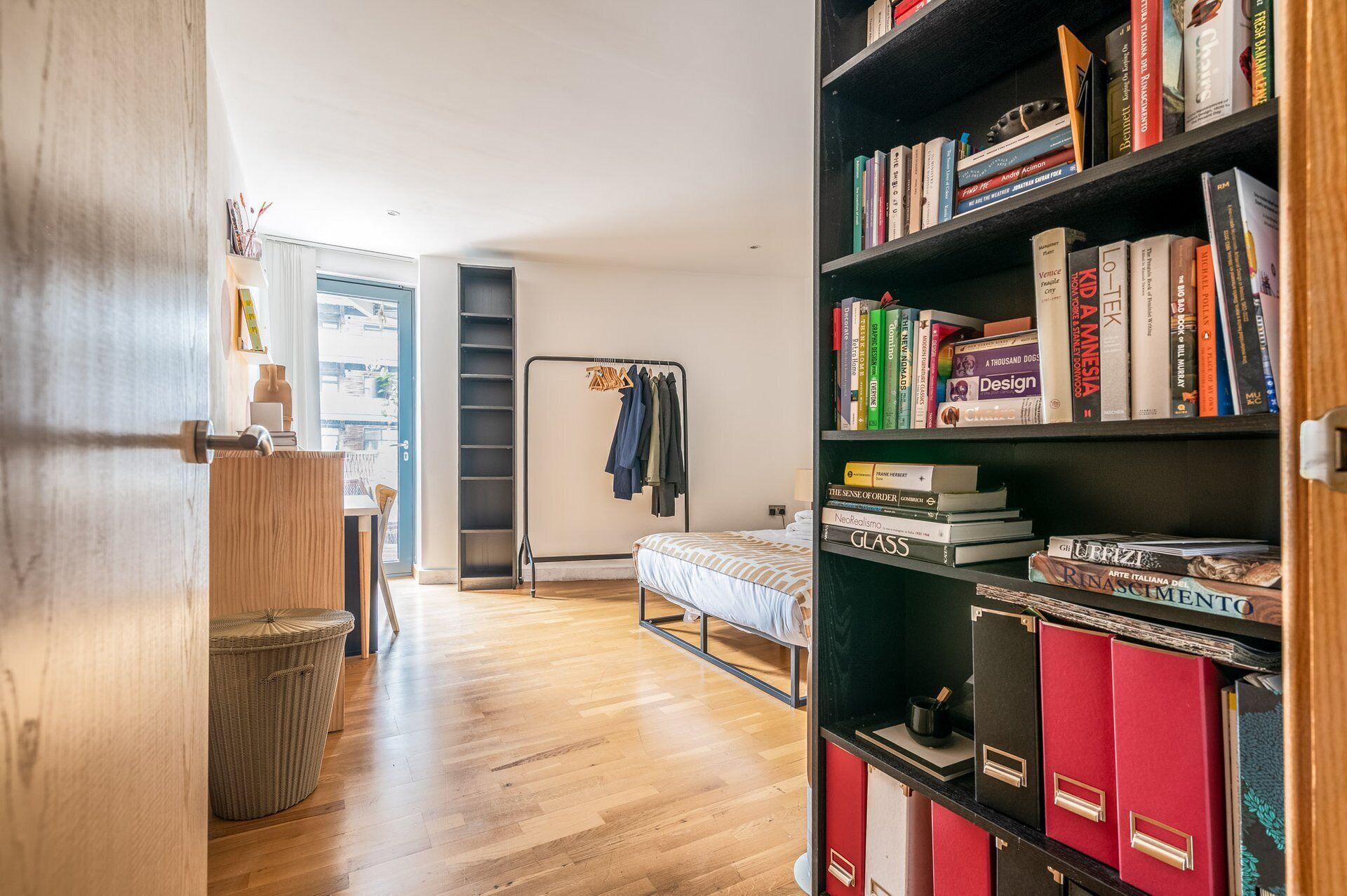 A room with a bed, a bookshelf, a wardrobe, and a window.