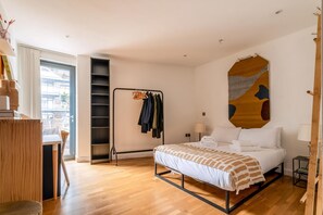 A modern bedroom with a bed, a wardrobe, a desk, and a window. - Stylish Hackney Wick Home (London)