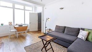 Ett modernt vardagsrum med en grå soffa, ett matbord i trä och ett litet sidobord.