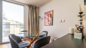 Un coin repas avec une table en verre, deux chaises, une affiche au mur et un narguilé placé sur le côté droit.
