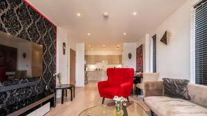 Un salon moderne avec un fauteuil rouge, un canapé beige et une table basse en verre.