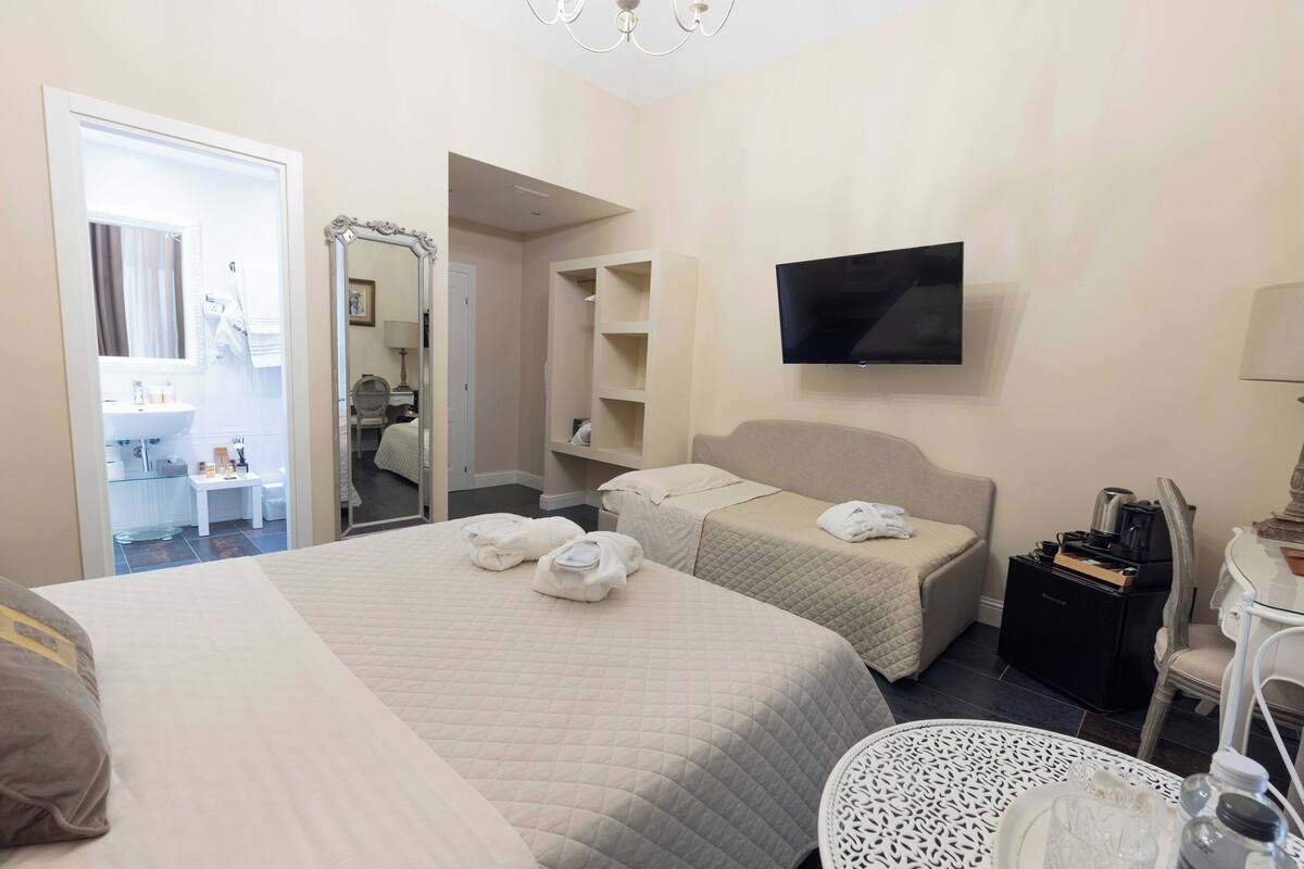 A hotel room with two beds, a TV, a desk, and a chair.