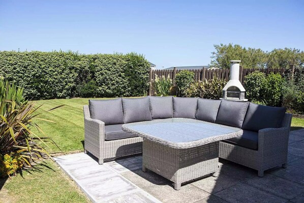 Ein Ecksofa mit Glastisch, Kamin aus Naturstein und ein gepflegter Garten.