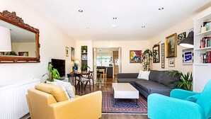 A modern living room with a sofa, armchairs, a coffee table, and a dining area. - Terraced Bermondsey House (London)