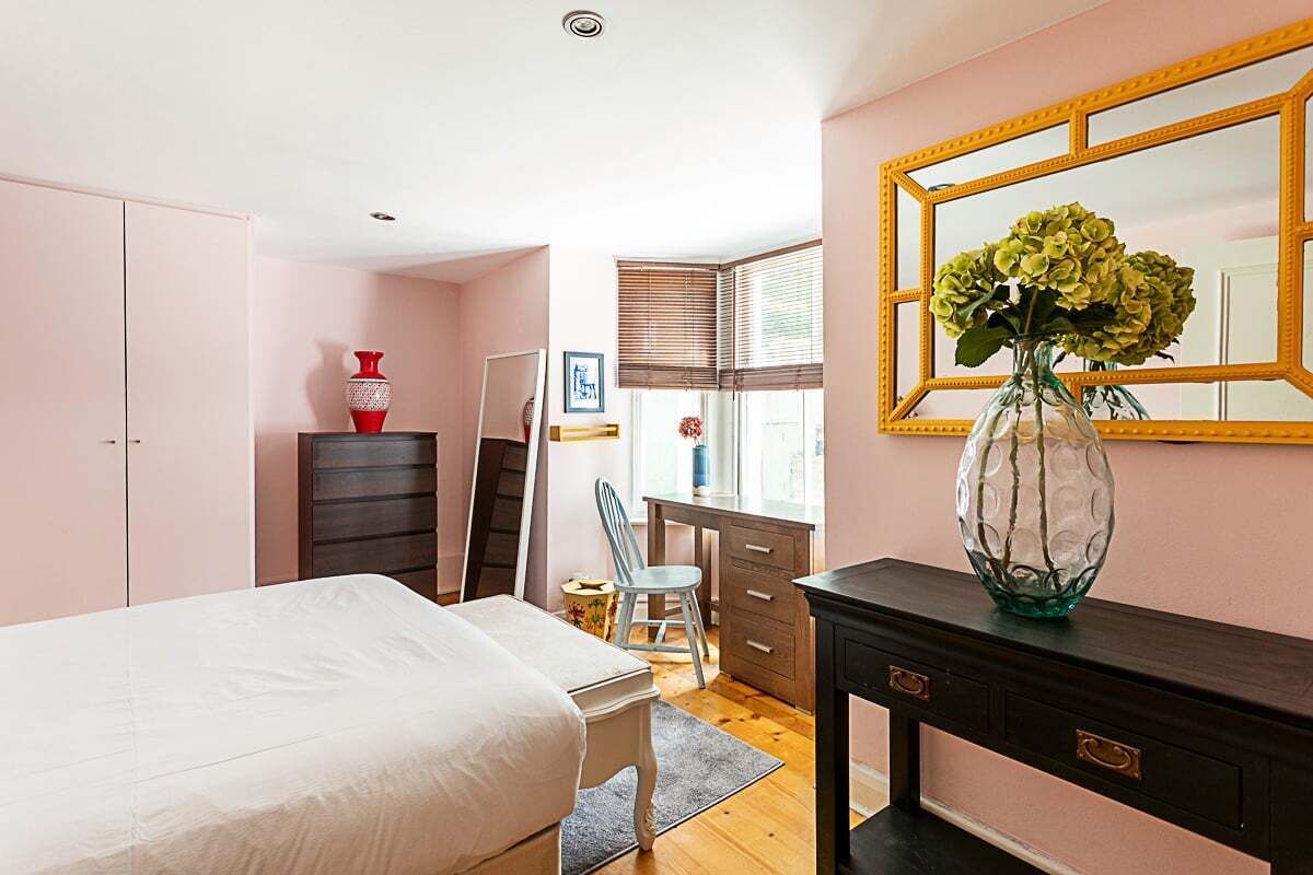 A bedroom with a bed, dresser, desk, chair, and a large mirror.