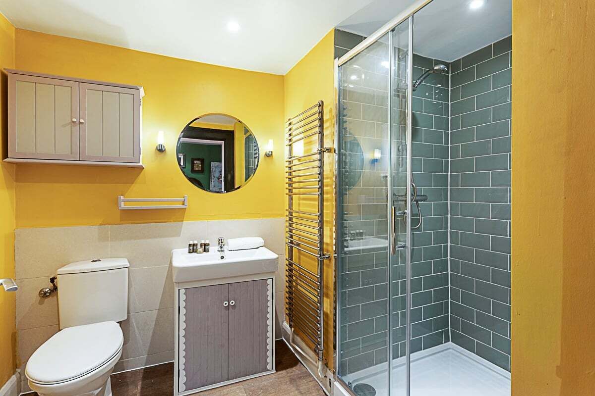 A bathroom with a toilet, sink, mirror, and a glass-enclosed shower.