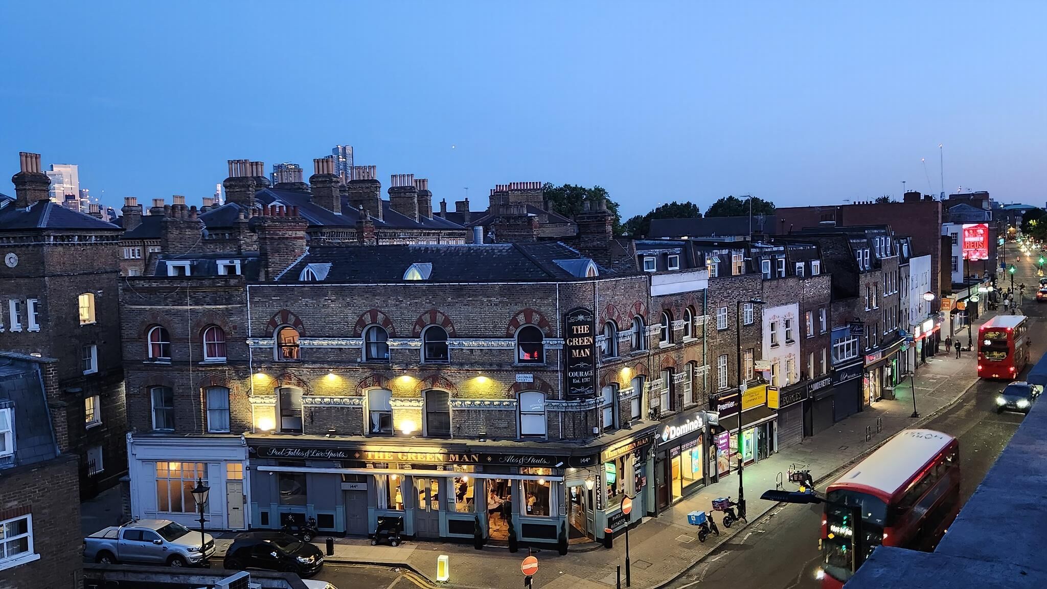 A street view with buildings, a pub named 'The Green Man,' and a red bus.