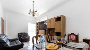 A dining area with a wooden table set for two, a water bottle, a bowl of fruit, and a bottle of wine.