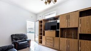 A living room with a black leather sofa, wooden cabinets, and a flat-screen TV.