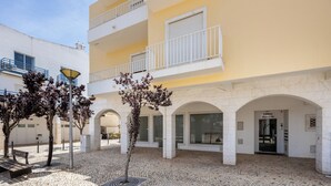 Un patio con suelo de adoquines, arcos blancos y la entrada de un edificio identificado como 'Edificio Alamo III'.