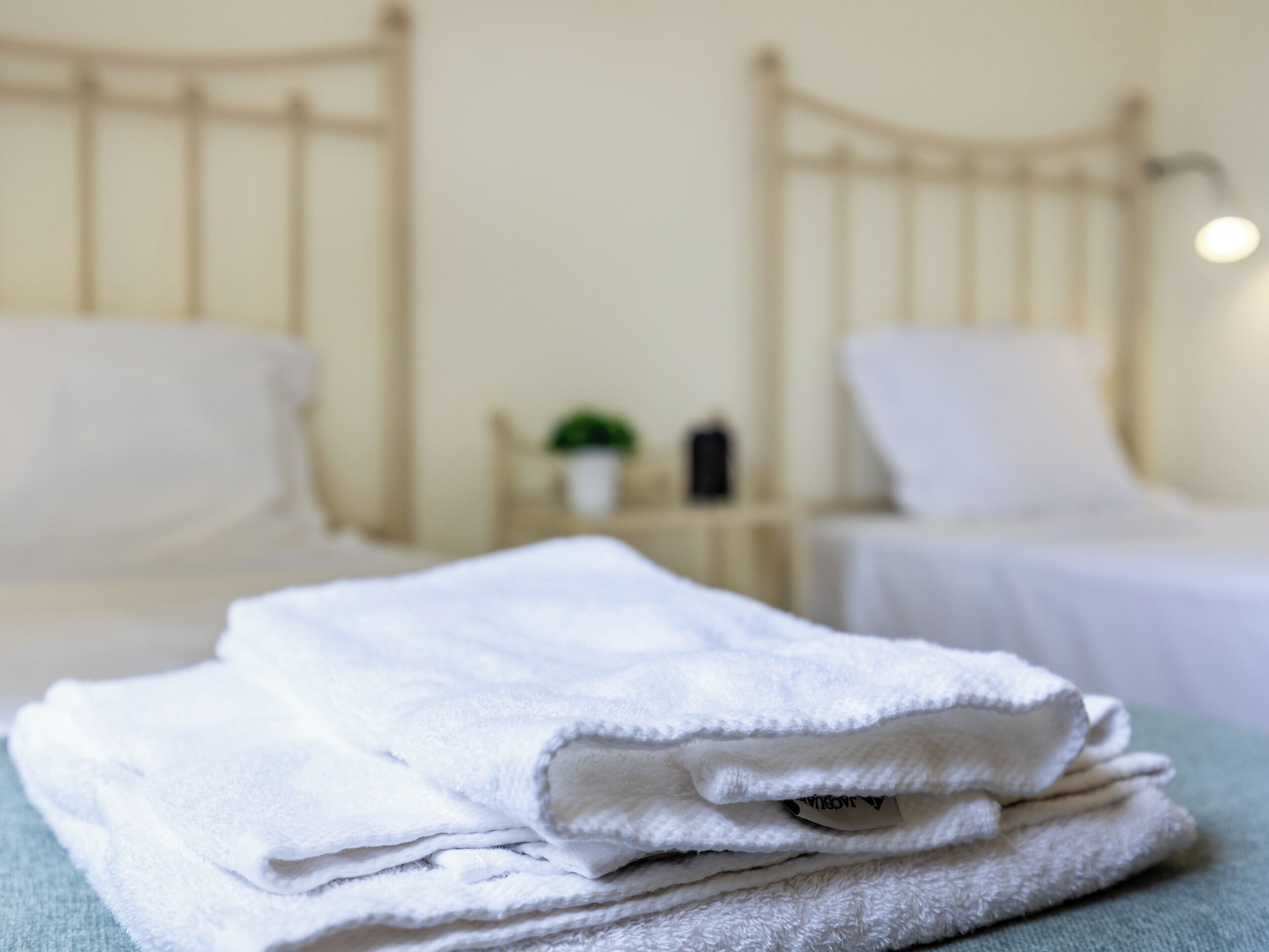 A neatly made bed with white linens and a small bedside table with a lamp.