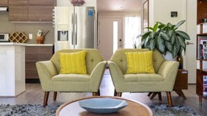 A living room with two armchairs, a coffee table, a large plant, and a bookshelf. - Somms Rest ⎮ Designed. Curated. Peaceful. (Forestville)