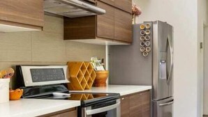 A modern kitchen with wooden cabinets, a stainless steel refrigerator, and a built-in oven. - Somms Rest ⎮ Designed. Curated. Peaceful. (Forestville)