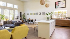 A modern living room with a sofa, yellow chairs, a dining area, and a kitchen island. - Somms Rest ⎮ Designed. Curated. Peaceful. (Forestville)