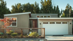 A modern two-story house with a garage, a fenced yard, and a tree with autumn leaves. - Somms Rest ⎮ Designed. Curated. Peaceful. (Forestville)