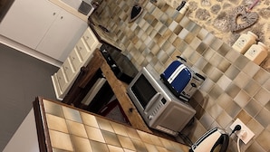 Una cucina con piastrelle a parete, un forno a microonde, un tostapane e un bollitore.