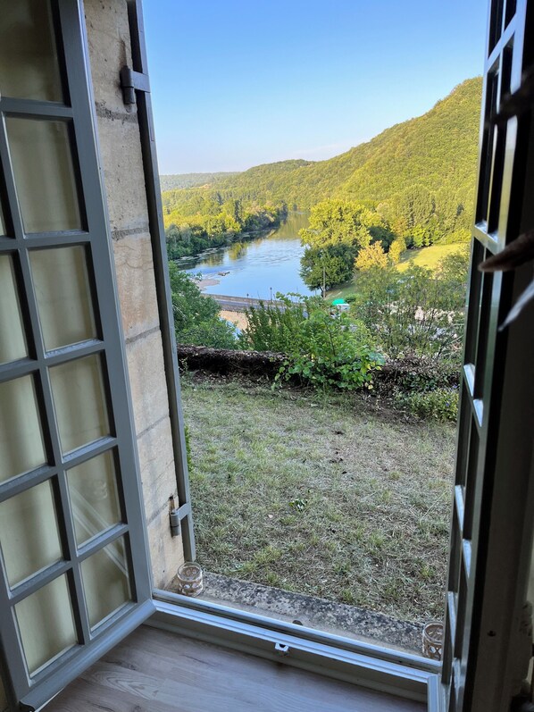 An open door with a view of a river, greenery, and hills.